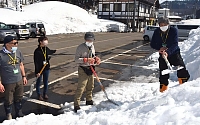 キャンドルを設置する雪の土台をシャベルで固める結いの元メンバーら＝１１日午前１１時１６分、栄村のＪＲ飯山線森宮野原駅前
