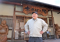 温泉前に立つ伊東富男さん。「常連客には会長さんて呼ばれるけど、もう何の肩書もないんだ」と笑う
