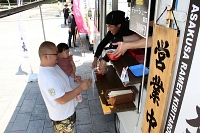 広場に並ぶキッチンカーでラーメンを買い求める来場者