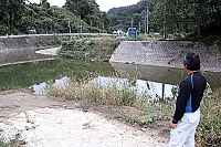 自宅近くの土尻川を見つめる男性。普段は穏やかな川が７月の大雨であふれた＝７日、小川村