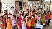 カンボジアの小学校で「手をピカピカ大作戦」を終え、両手を掲げた子どもたちと記念撮影する大西彩桜さん（右下）＝２月（大西さん提供）