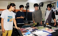 写真を見て印象を語り合う松本深志高校写真研究会の（左から）小林祈織さん、土屋篤史さん、小川天佑さん、遠藤武弥さん。暗室だった部室には、引き伸ばし機（後方）などフィルムカメラ用の機材もある