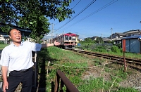 上田電鉄別所線の三好町駅近くで脱炭素先行地域事業について語る山岸さん。線路脇が広く、太陽光パネルを並べる場所に想定している＝１日