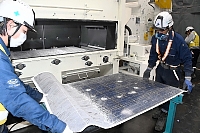 リサイクルに向けて処理中の太陽光パネル。手前左側の灰色の部分は、表面のガラスが粉砕されている。右側の黒い部分はガラスが付いた状態＝諏訪市の信州タケエイ