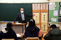藤村直筆の掛け軸について説明する加藤さん（中央奥）