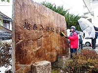 越県合併の記念碑をブラシでこすり、汚れを落とす児童＝１２日午後３時５９分、岐阜県中津川市