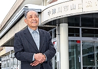 山口村最後の村長を務めた加藤出さん。旧山口村役場の建物前で越県合併からの２０年を振り返った＝７日、岐阜県中津川市