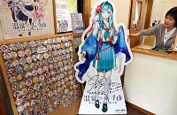 「別所愛染」のパネルがある上田電鉄別所温泉駅内の案内所。ファンが「奉納」した全国の温泉むすめのバッジなどが飾られている