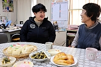 豊田地域の農産物を使ったおやきやアップルパイを前に、西野組合長（右）に訪日客ツアー受け入れを依頼する池田さん＝１８日、中野市永江
