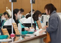 新たな行名やロゴマークが入った法被を着て営業初日の業務に臨む職員たち＝5日午前9時27分、長野市の八十二長野銀行本店営業部