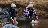悩み事を託したひな人形を相木川に流す児童たち