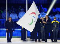 ミラノ・コルティナ冬季パラリンピックの閉会式で、次回大会の開催地フランス・アルプス地域に引き継がれたパラリンピック旗。左端はIPCのパーソンズ会長＝15日、イタリア・コルティナダンペッツォ（共同）
