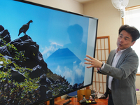 岩場に立つライチョウと富士山の対比が美しい作品を解説する秦さん