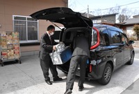 デリシア軽井沢店でタクシーに食品などを運び入れる運転手（左）