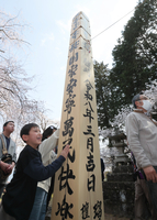 回向柱に触れて笑顔を見せる子ども