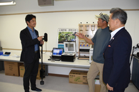 八ケ岳農業大学校に新設したラボで土壌分析装置を手にする（左から）小松CEO、丸山校長、諏訪信金の田中理事長