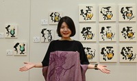 「酒」の古代文字を使ってデザインした作品の前に立つ和全さん