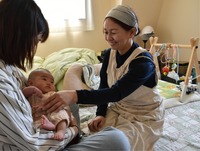 助産院おりんに宿泊した母子に語りかける北沢さん（右）