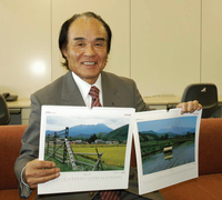 自ら撮影した伊那・木曽谷の風景カレンダーを手にする塚越寛さん＝2005年11月、伊那市