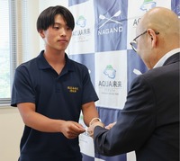 県ローイング協会の激励金を受け取る佐野さん（左）