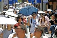 　猛暑日となった福岡県太宰府市で日傘を差して歩く人たち＝11日午前