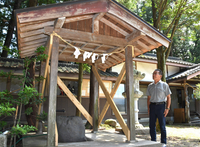 修繕した手水舎と横に立つ奥原さん