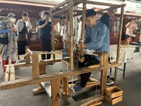 上田駅ホームで機織りをする小岩井さん。ろくもんの乗客が興味深そうに見入った