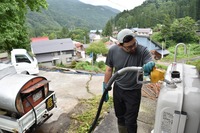 民宿のタンクに灯油を注ぐ砂川さん＝7月16日午前11時半ごろ、栄村の秋山郷