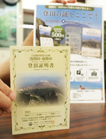 リニューアルした登頂証明書（左）とPR用のチラシ