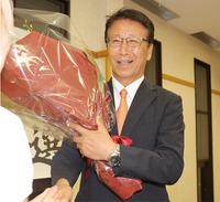 3選を果たし、花束を手に支持者と握手する横前明氏＝9日午後9時8分、泰阜村平島田