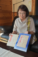 父親の著書を手にするあつ子さん。左が絶版、右が再出版した書籍