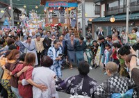 切子灯籠の行列（奥）の行く手を阻むように肩を組んで踊る若者ら＝17日午前5時45分、阿南町新野