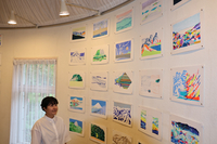 個展会場で、壁一面に並べたドローイングを眺める立原さん