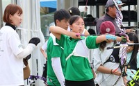 早川さん（左端）の指導を受けて構える武田さん（中央）