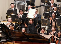 「トゥランガリーラ交響曲」の演奏を終え、スコアを掲げて客席の拍手に応える沖澤さん＝8月22日、松本市のキッセイ文化ホール