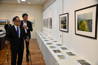 塚越さんのお別れの会に参列し、追悼展の会場を見て回る豊田会長（手前）