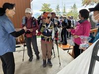 登山者にキーホルダーを配るシャーロックさん（左）たち＝6日、木曽町