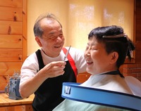常連客の金田伸子さん宅で金田さんの髪を切る佐藤広忠さん（左）＝9日、阿南町