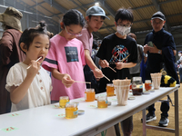 養蜂家が持ち寄った蜂蜜の味を確かめる来場者