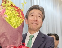 再選を確実にし、花束を手に笑顔の百瀬敬氏＝20日午後9時8分、塩尻市大門一番町