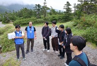 田の原登山口近くで御嶽山について説明する火山マイスター（左）。火山防災や山の魅力を発信する人材の充実に期待する遺族らも多い＝7月19日、王滝村