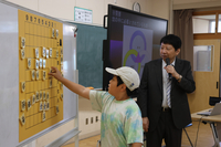 巨大な将棋盤で小学生らと対局する杉本さん（右）