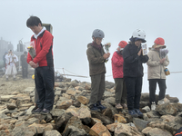御嶽山頂の剣ケ峰で、噴火時刻の午前11時52分に合わせて犠牲者を追悼する遺族ら