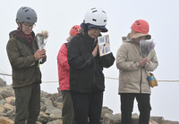 噴火時刻に合わせて黙とうする、犠牲者の寄能啓二さんのいとこの江藤領さん（右）ら、親族の4人＝27日午前11時52分、御嶽山頂の剣ケ峰