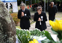 慰霊碑の前で献花し、手を合わせる遺族＝27日午後0時9分、王滝村