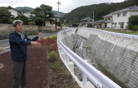 改良復旧が終わった田子川を前に当時を振り返る水間さん＝6日、佐久市