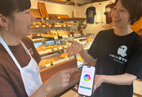 ストレスチェックや、その後の健康管理機能を備えたシステムを店員に説明する安田妃佐社長（右）＝諏訪市の「太養パン店」