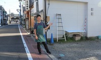 下諏訪駅（左奥）と国道をつなぐ駅前通りに整備するカネキ商店の予定地を紹介する本田さん