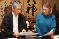 近年の御神渡りの記録をキャロルさん（右）に見せる宮坂宮司