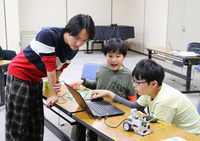 山口さん（左）にプログラミングを教わる子どもたち